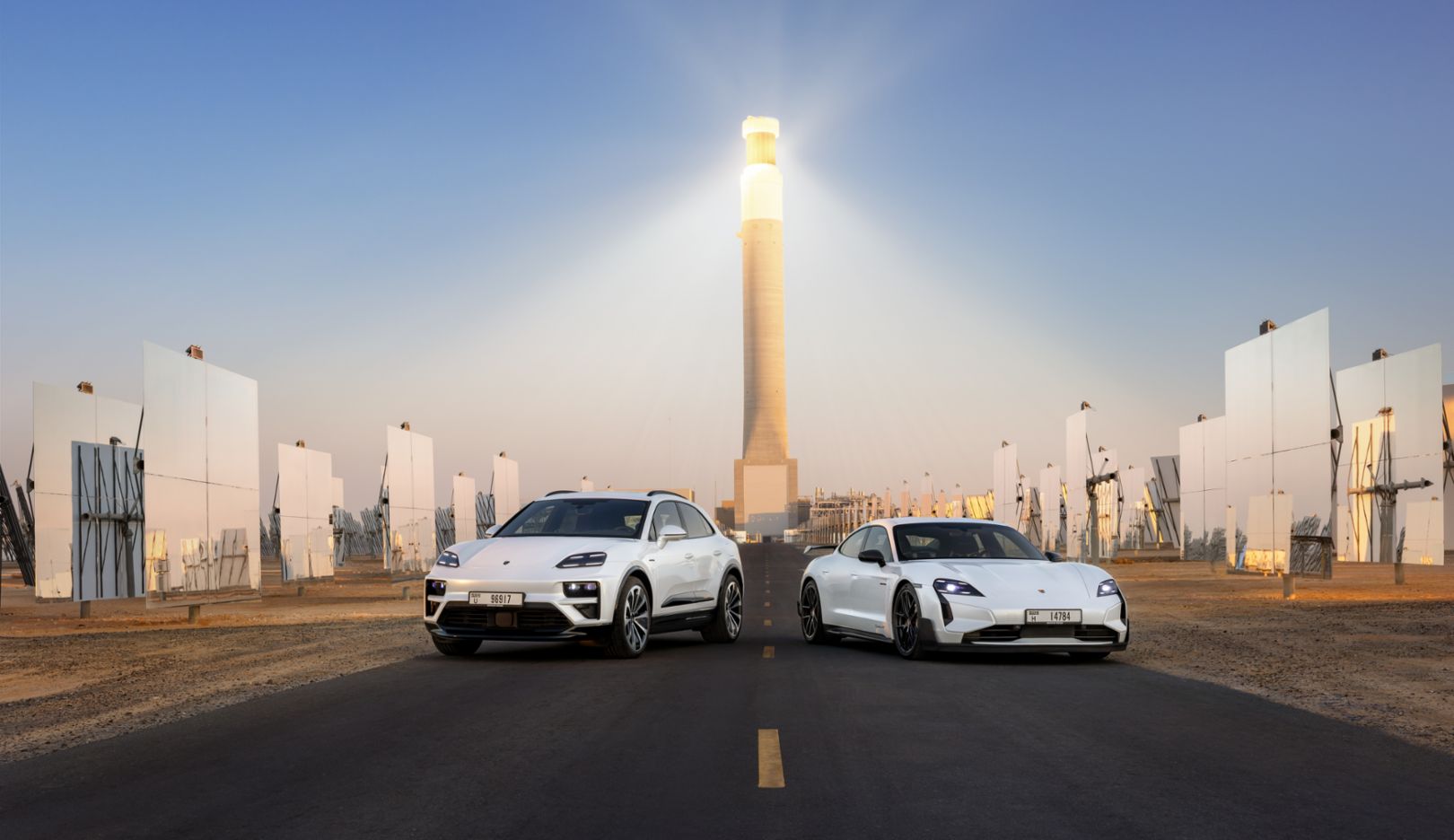 Macan Turbo e Taycan Turbo GT com pacote Weissach em Dubai, em frente à torre solar mais alta do mundo.