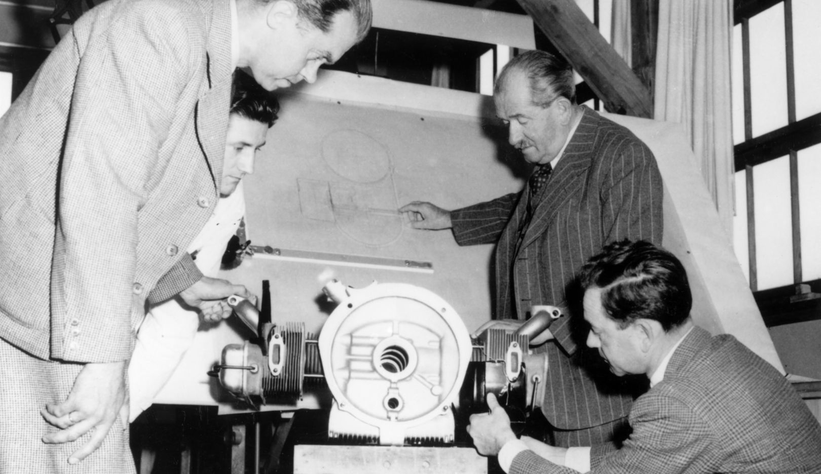 1950: Ferry Porsche (na dole po prawej) z ojcem Ferdinandem Porsche (z ręką na desce kreślarskiej) w ówczesnym biurze projektowym Porsche w Stuttgarcie-Zuffenhausen. Z przodu po lewej konstruktor silników Leopold Jäntschke.