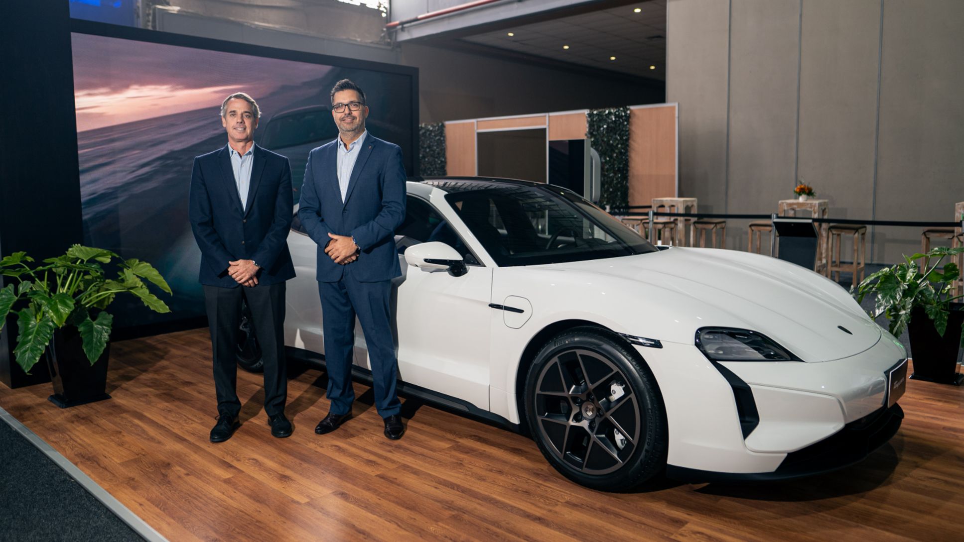 Gonzalo Flechelle, Gerente de Porsche Perú, y José Luis Cabré, Gerente de Postventa de Porsche Latin America, al lado del nuevo Taycan Turbo, color blanco, en Transporte Sostenible, evento de energías limpias más importante del país, que se está llevando a cabo en el Centro de Exposiciones Jockey Club del Perú, en Lima, Perú, Porsche AG.