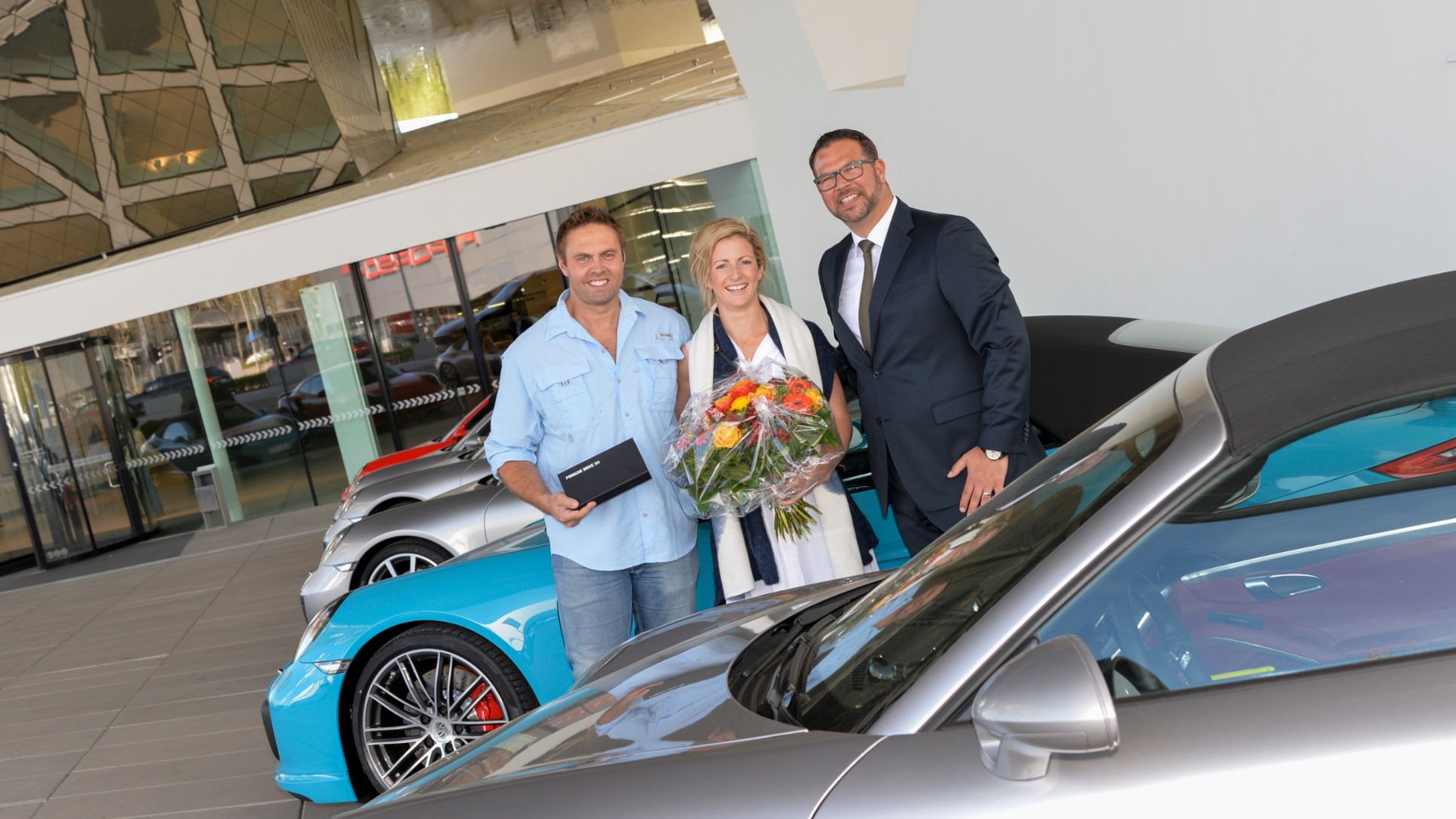 Achim Stejskal (der.), Director del Museo Porsche, sorprendió a Justine (centro) y David Boscaglia con un regalo muy especial: la posibilidad de elegir cualquier vehículo de la gama actual para conducirlo durante todo un fin de semana.