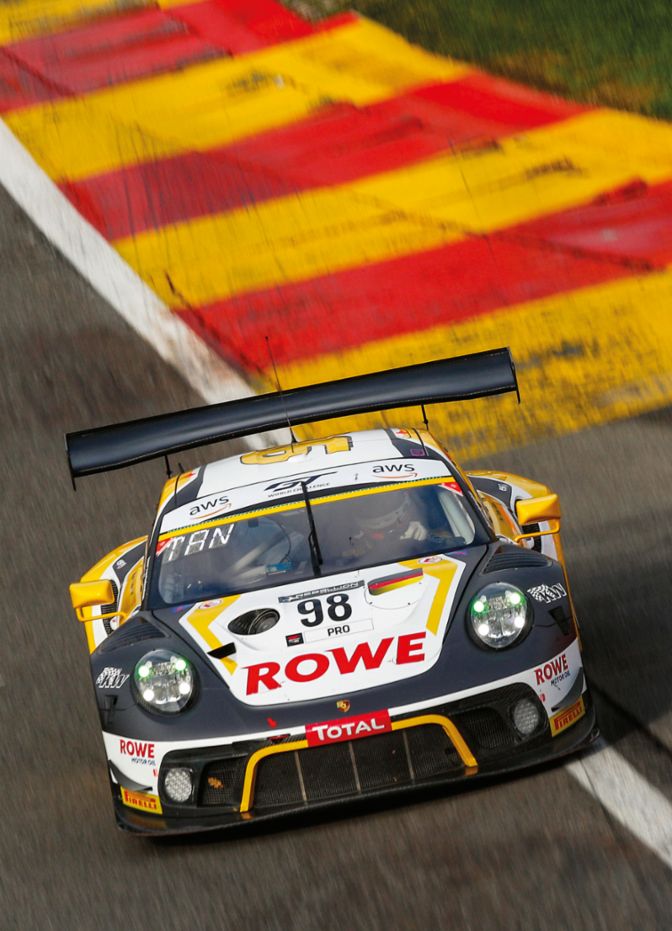 A race car with the number 98 drives on a track with colored edge markings and a dynamic curve.