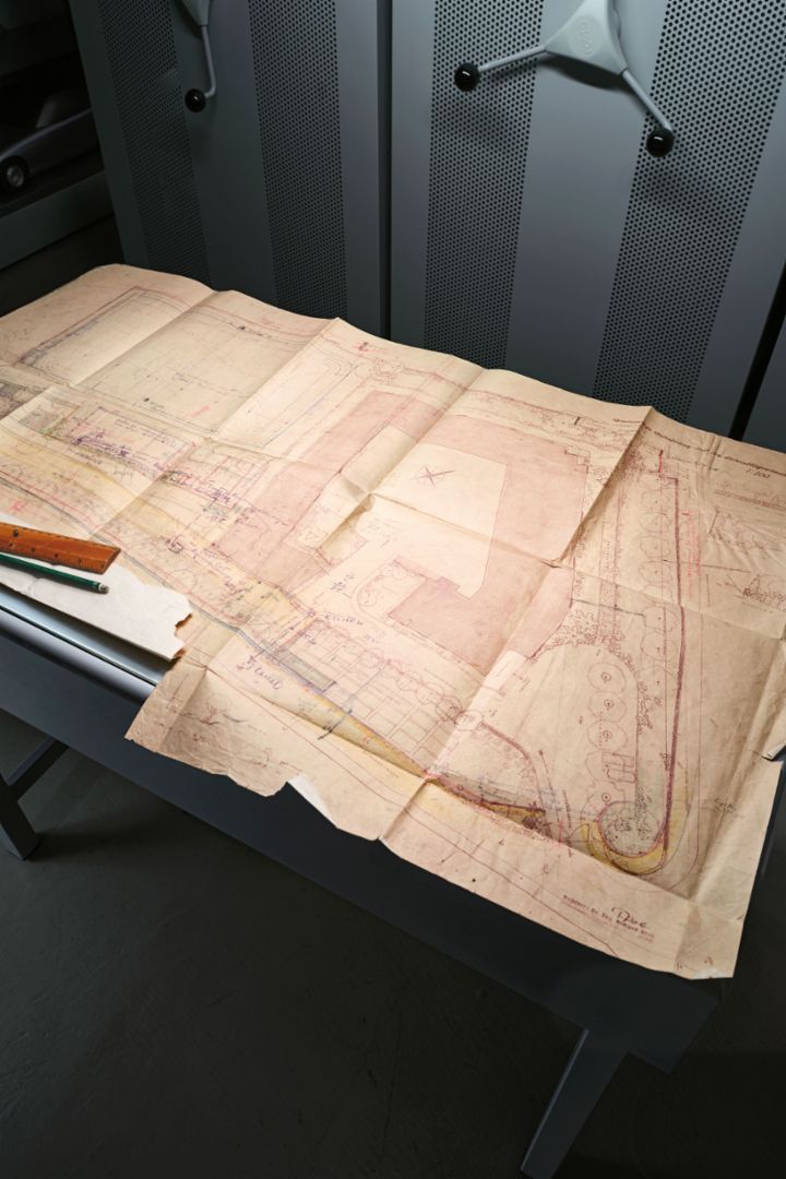 An old plan lies on a table, surrounded by a ruler and in an archive room.