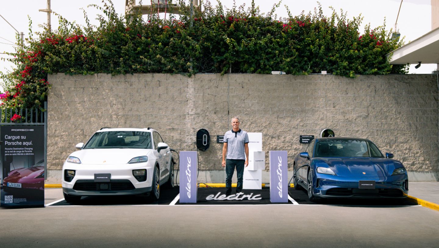 Gonzalo Flechelle, Gerente de Porsche Perú, en medio del nuevo Macan 4 electric, color gris ice y del Taycan color azul gentian, en la inauguración de un nuevo punto de carga para vehículos eléctricos, en el supermercado Vivanda Asia, al sur de Lima, Lima, Perú, Porsche AG.