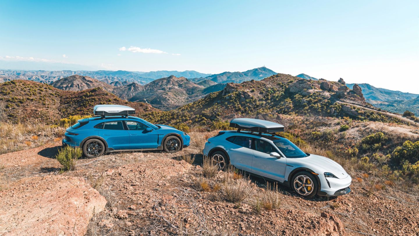 Two Taycan Cross Turismo Turbo with roof rack cargo off road on a desert landscape