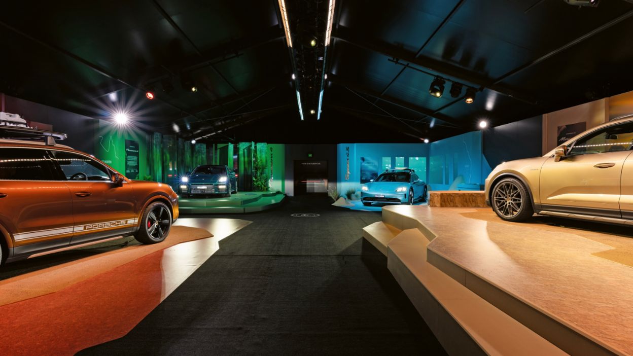 Several vehicles are displayed on raised platforms inside a lit exhibition hall.